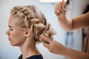 Female hairdresser making hairstyle to blonde girl in beauty salon